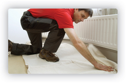 Service engineer laying a dustsheet before a powerflushing